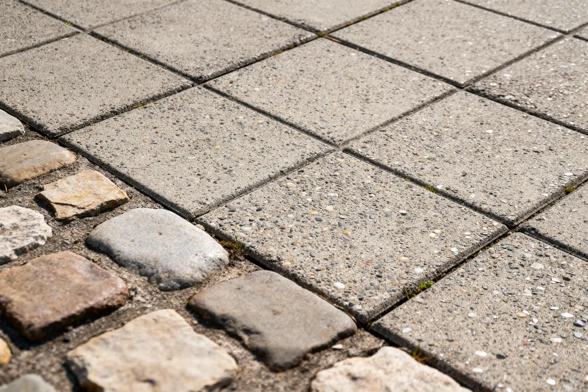 Pavés de pierre et dalles en béton côte à côte, formant un chemin contrasté et texturé.