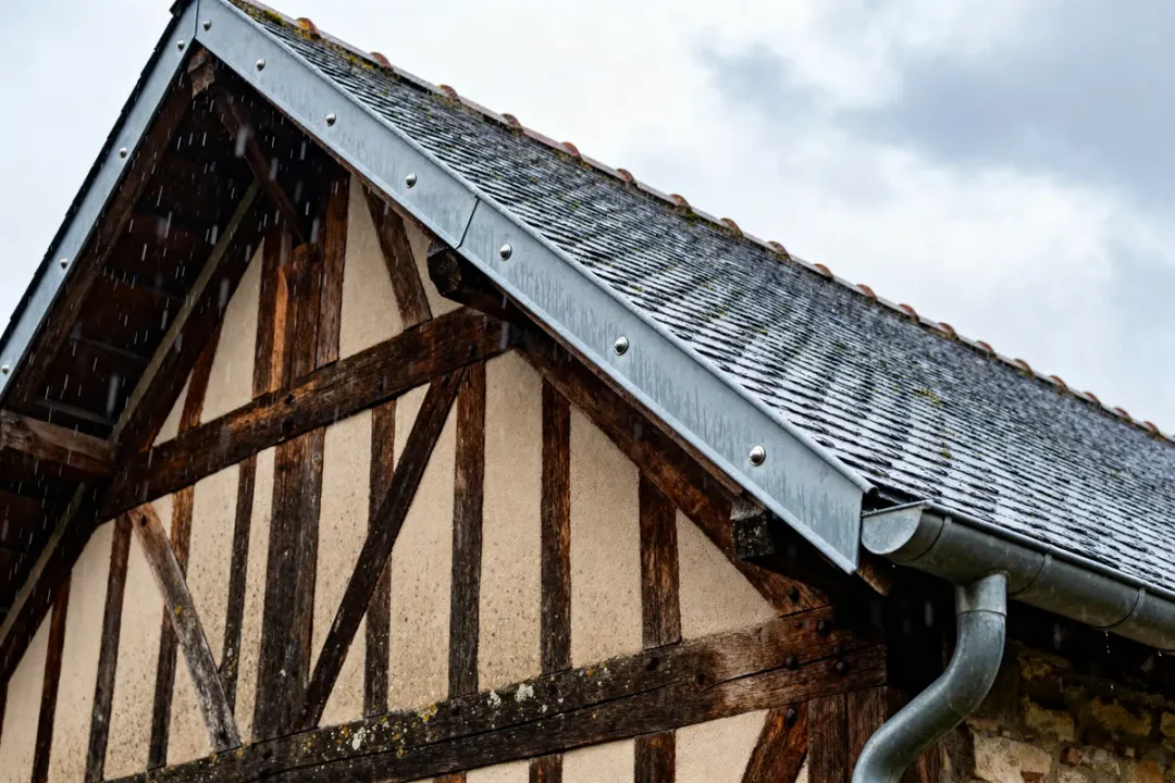 Toit en ardoise avec chéneau toiture et colombages en bois sous la pluie légère