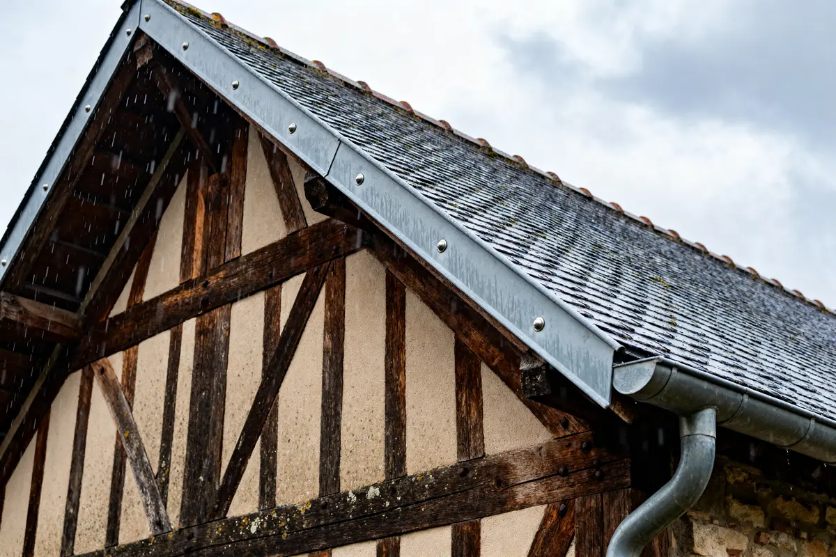 Toit en ardoise avec chéneau toiture et colombages en bois sous la pluie légère