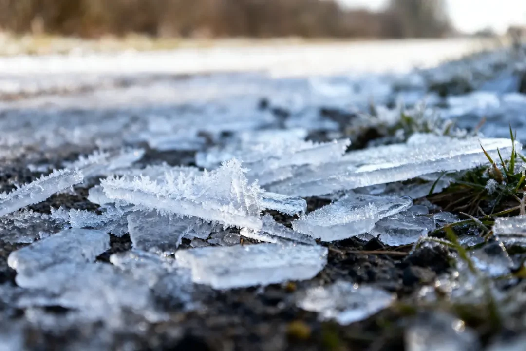 Morceaux de glace fondue sur sol herbeux évoquant dégivrer congélateur très encrassé efficacement