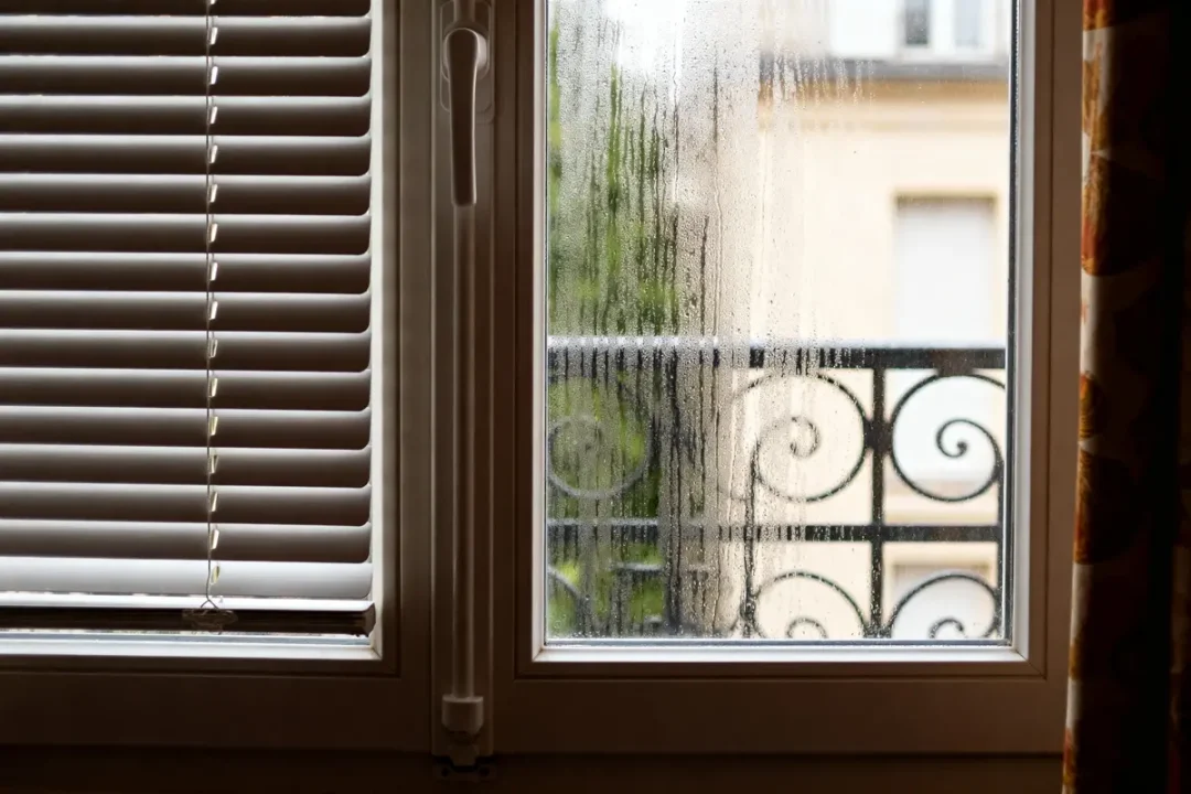 Fenêtre PVC aération avec condensation et volet intérieur partiellement fermé
