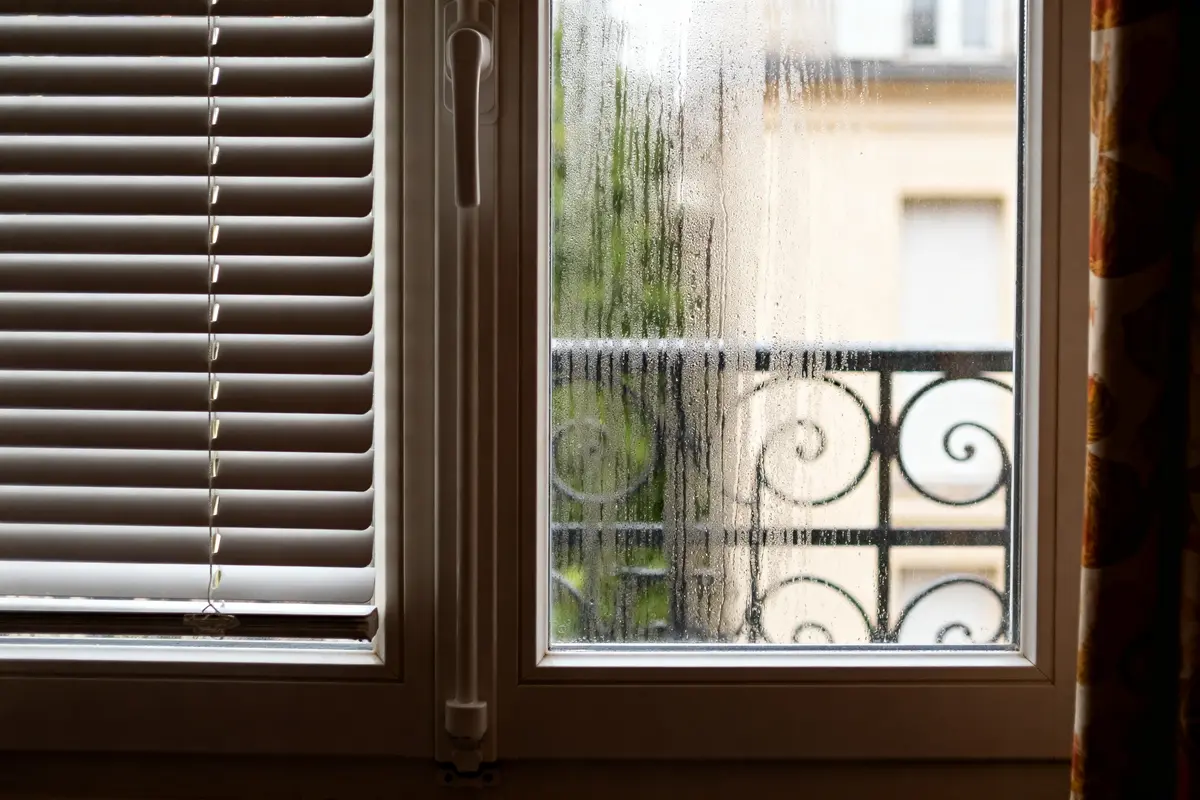 Fenêtre PVC aération avec condensation et volet intérieur partiellement fermé